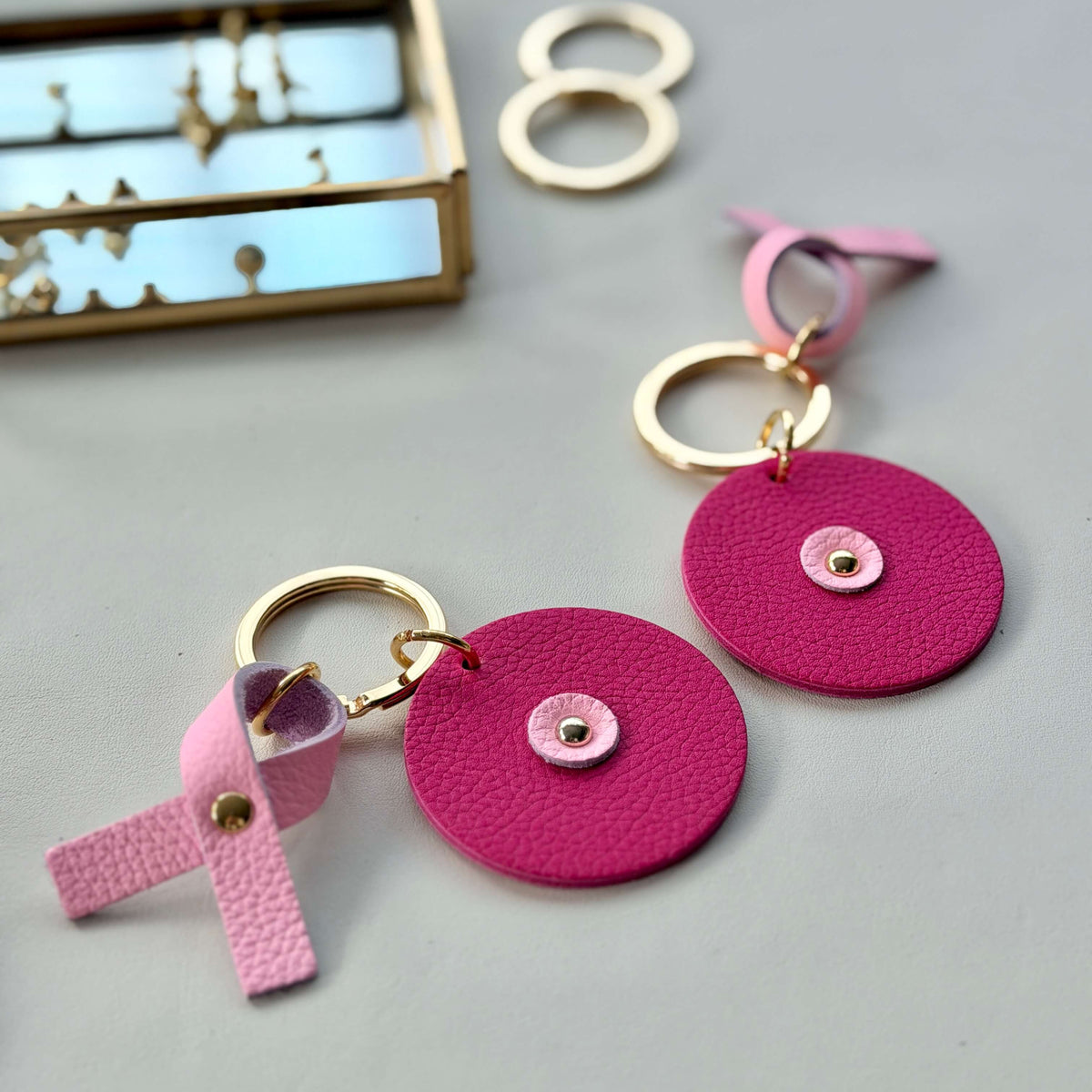 Porte-clés ronds Atelier Guillocher en cuir rose fuchsia avec ruban Octobre Rose pour la Ligue contre le cancer
